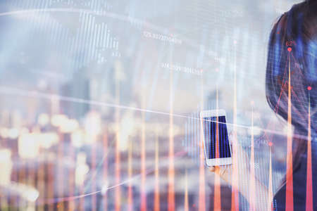 Double exposure of forex chart sketch hologram and woman holding and using a mobile device. Stock...