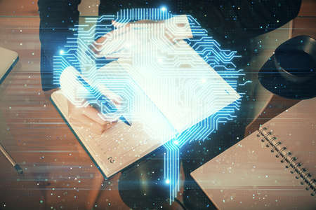 Double exposure of writing hand on background with brain hologram. Concept of learning.