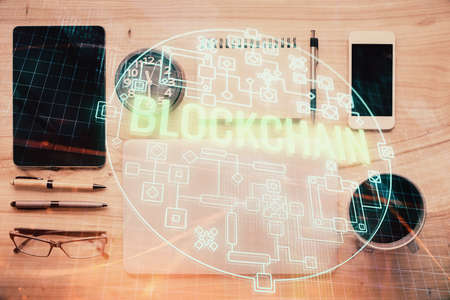Double exposure of blockchain theme hologram over table with phone. Top view. Crypto technology...