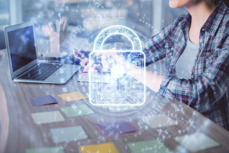 Double exposure of woman hands working on computer and lock hologram drawing. Security concept.