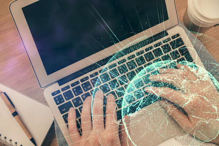 Double exposure of man's hands typing over computer keyboard and social network theme hologram...