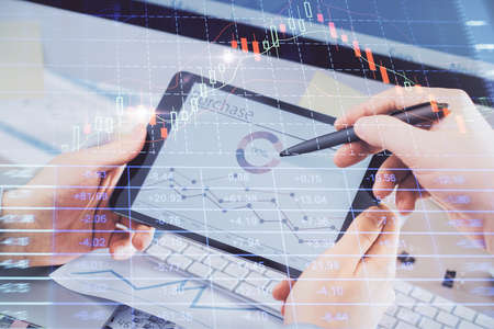 Double exposure of man's hands holding and using a phone and financial chart drawing. Market...