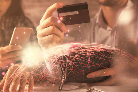 Double exposure of man and woman on-line shopping holding a credit card and social network theme hologram drawing. People connecting and E-commerce pay on-line concept.の写真素材