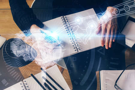 Double exposure of writing hand on background with brain hologram. Concept of learning.