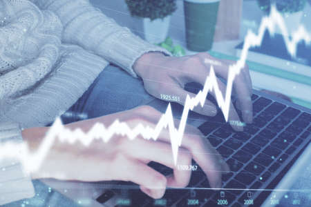 Double exposure of woman hands typing on computer and forex chart hologram drawing. Stock market...