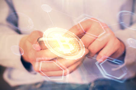 Double exposure of man's hands holding and using a phone and crypto currency blockchain theme...