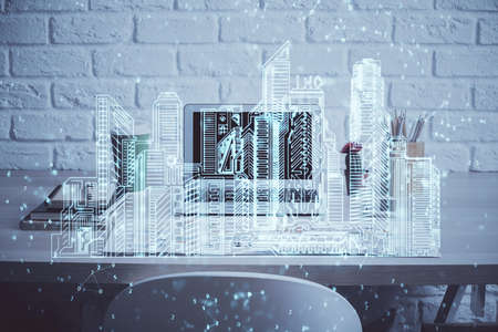 Desktop computer background in office and big town buildings hologram drawing. Double exposure....