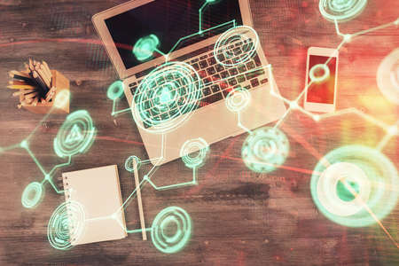 Social network hologram drawings over computer on the desktop background. Top view. Multi exposure....