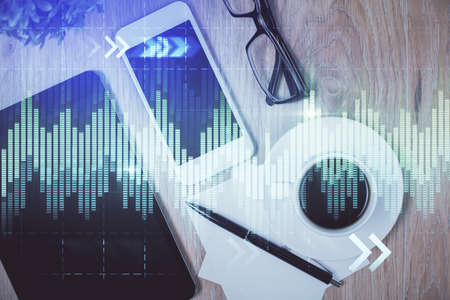 Double exposure of forex chart hologram over desktop with phone. Top view. Mobile trade platform...
