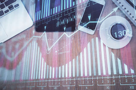 Double exposure of financial graph hologram over desktop with phone. Top view. Mobile trade platform concept.の写真素材