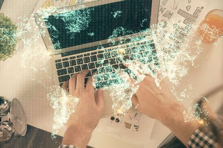 Double exposure of man's hands typing over computer keyboard and social network theme hologram...
