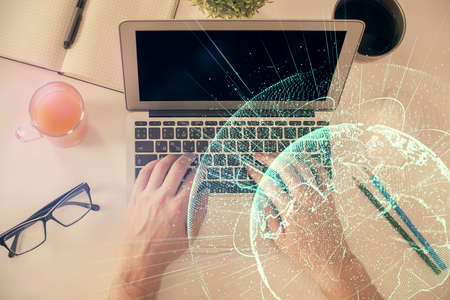 Double exposure of man's hands typing over computer keyboard and social network theme hologram...