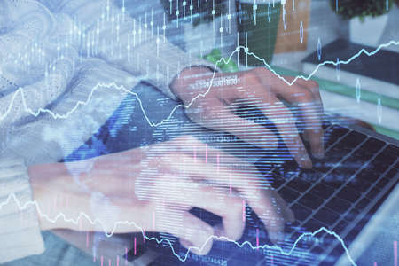 Double exposure of woman hands typing on computer and forex chart hologram drawing. Stock market...