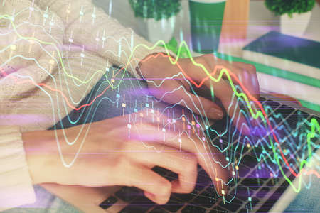 Double exposure of woman hands typing on computer and forex chart hologram drawing. Stock market...