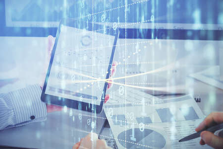 Double exposure of man's hand holding and using a digital device and data theme hologram drawing....