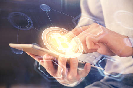 Double exposure of man's hands holding and using a phone and crypto currency blockchain theme...