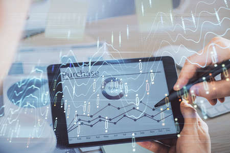 Double exposure of man's hands holding and using a phone and financial chart drawing. Market...