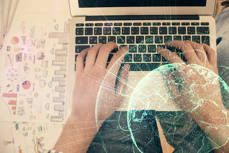 Double exposure of mans hands typing over computer keyboard and social network theme hologram...
