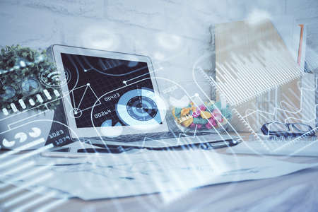 Computer on desktop in office with technology theme hologram. Double exposure. Tech concept.