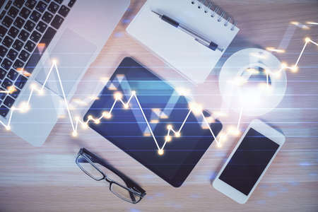 Multi exposure of forex graph hologram over desktop with phone. Top view. Mobile trade platform...
