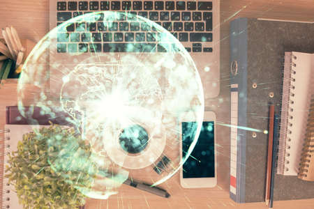 Double exposure of business theme hologram over desktop with phone. Top view. Mobile international trade connection concept.の写真素材