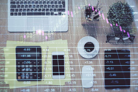 Double exposure of forex chart hologram over desktop with phone. Top view. Mobile trade platform...