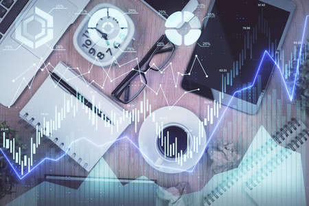 Double exposure of financial chart hologram over desktop with phone. Top view. Mobile trade platform...