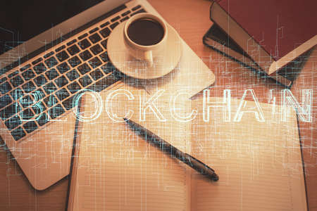 Blockchain theme hologram drawings over computer on the desktop background. Top view. Double...