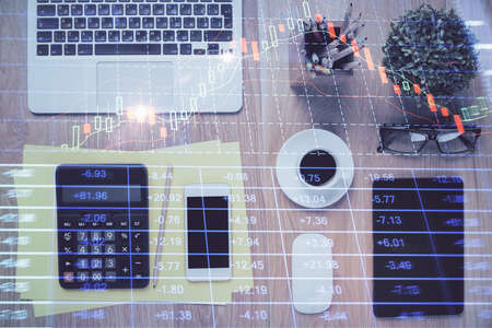 Double exposure of forex chart hologram over desktop with phone. Top view. Mobile trade platform...