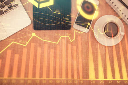 Double exposure of financial chart hologram over desktop with phone. Top view. Mobile trade platform concept.の写真素材
