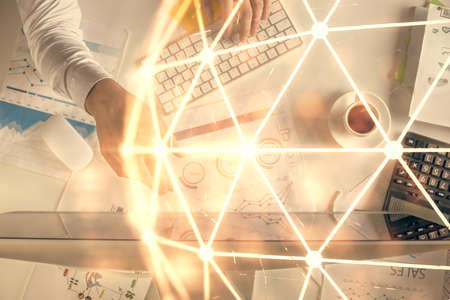 Double exposure of mans hands typing over computer keyboard and social network theme hologram...