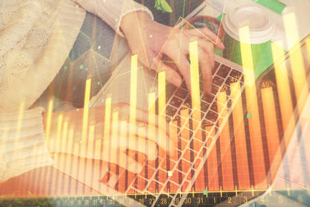 Double exposure of woman hands typing on computer and forex chart hologram drawing. Stock market...