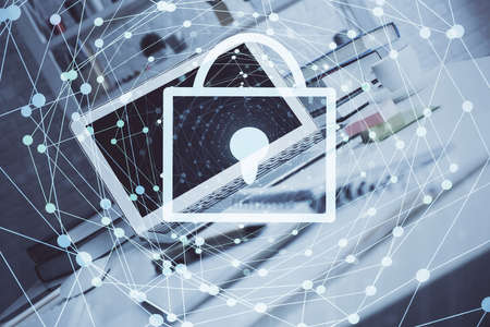 Double exposure of desktop with computer and lock icon hologram. Concept of data safety.