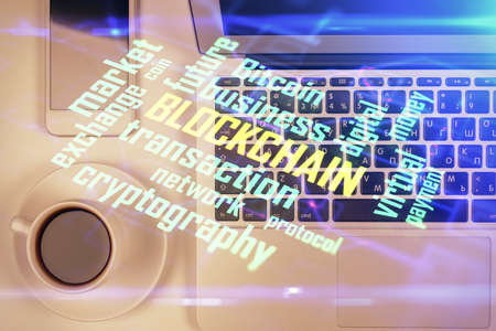 Blockchain theme hologram drawings over computer on the desktop background. Top view. Double...