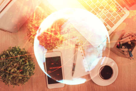 Double exposure of business theme hologram over desktop with phone. Top view. Mobile international trade connection concept.の写真素材