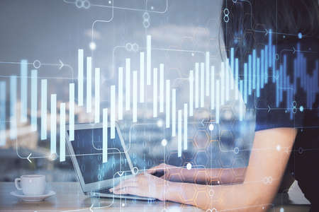 Double exposure of businesswoman hands typing on computer and forex chart hologram drawing....