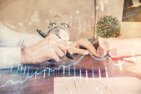Double exposure of mans hands holding and using a phone and financial graph drawing. Analysis concept.の写真素材