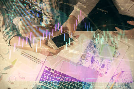 Double exposure of forex graph drawing and man and woman working together holding and using a mobile...