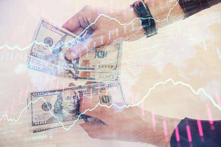 Multi exposure of financial graph drawing hologram and USA dollars bills and man hands. Analysis concept.の写真素材