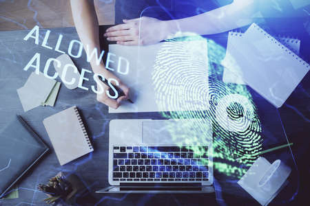 Blue fingerprint hologram over hands taking notes background. Concept of security. Double exposure