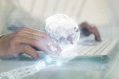 Double exposure of world map hologram with man working on computer on background. Concept of...