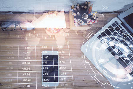 Double exposure of financial graph hologram over desktop with phone. Top view. Mobile trade platform...