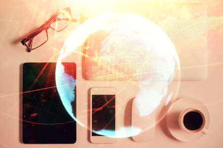 Double exposure of business theme hologram over desktop with phone. Top view. Mobile international trade connection concept.の写真素材