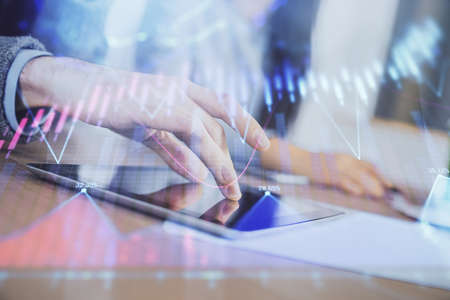 Double exposure of forex graph drawing and man and woman working together holding and using a mobile...