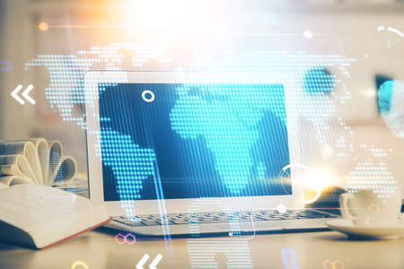 Double exposure of desktop with computer and world map hologram. International data network concept.の写真素材