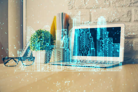 Desktop computer background in office and big town buildings hologram drawing. Double exposure....