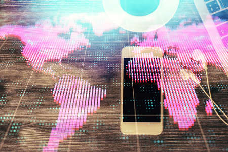 Double exposure of business theme hologram over desktop with phone. Top view. Mobile international...