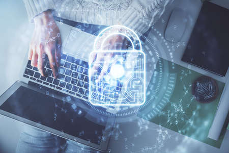 Double exposure of woman hands working on computer and lock hologram drawing. Top View. Security...