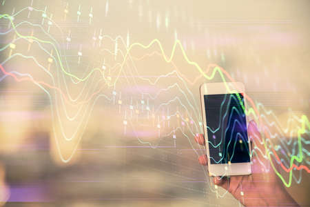 Double exposure of forex chart sketch hologram and woman holding and using a mobile device. Stock...