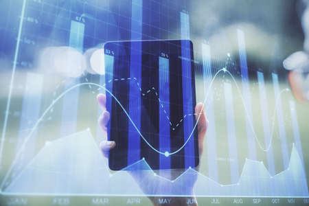 Double exposure of forex chart sketch hologram and woman holding and using a mobile device....